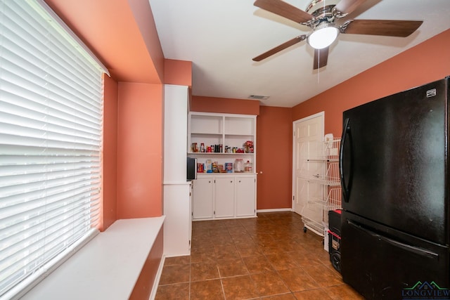 kitchen with dark tile patterned flooring, white cabinetry, and black fridge