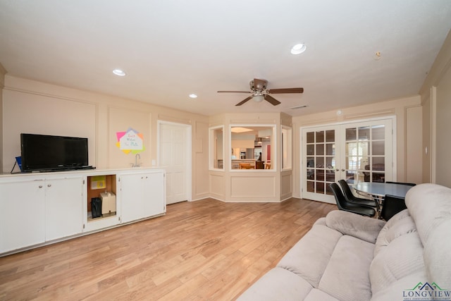 living room featuring ceiling fan, french doors, light hardwood / wood-style floors, and sink