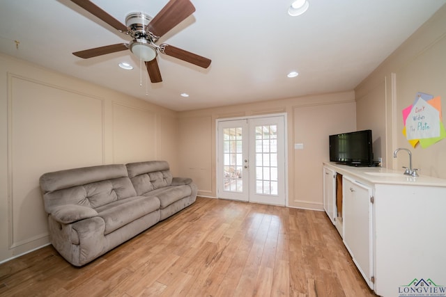 living room featuring french doors, light hardwood / wood-style floors, ceiling fan, and sink