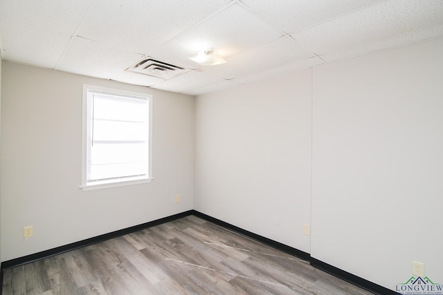 spare room featuring hardwood / wood-style floors and a drop ceiling