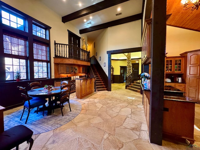 dining space featuring beam ceiling and a towering ceiling