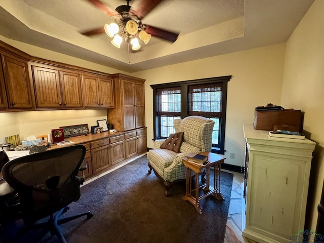 office with built in desk, a raised ceiling, and ceiling fan