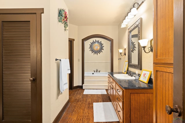 bathroom with a tub to relax in, vanity, and hardwood / wood-style flooring