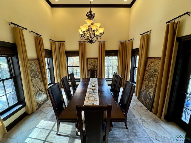 dining area featuring a chandelier, a towering ceiling, and ornamental molding