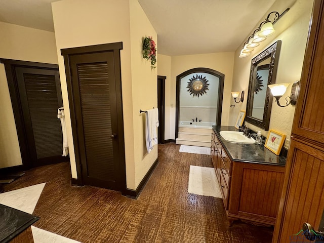 bathroom with a bathtub, vanity, and wood-type flooring