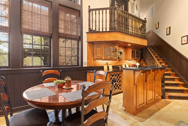 dining space featuring a towering ceiling, bar, and wood walls