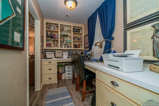 home office with built in desk and dark wood-type flooring