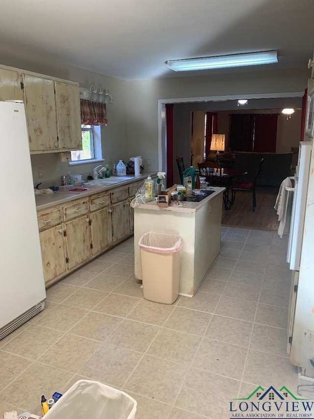 kitchen featuring sink, a center island, light tile patterned flooring, and white refrigerator