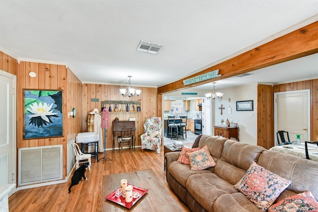 living room featuring crown molding, light hardwood / wood-style flooring, and a chandelier