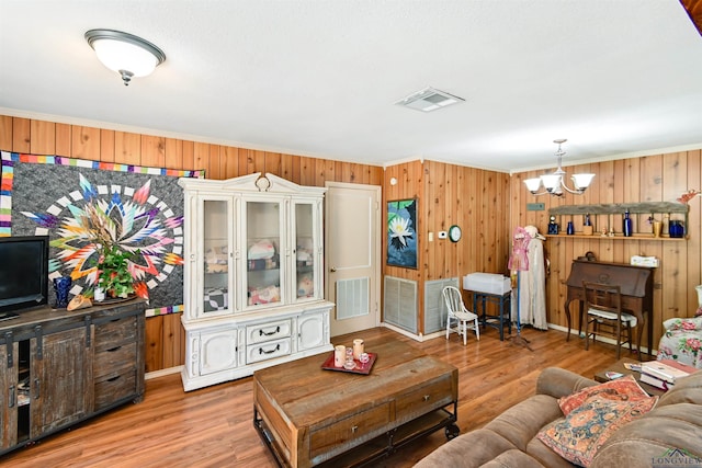 living room with hardwood / wood-style floors, ornamental molding, and a chandelier