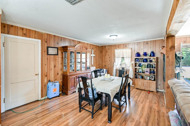 dining room featuring light hardwood / wood-style flooring, a textured ceiling, and ornamental molding