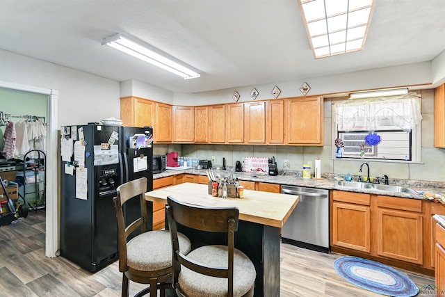 kitchen featuring dishwasher, sink, black refrigerator with ice dispenser, decorative backsplash, and light wood-type flooring