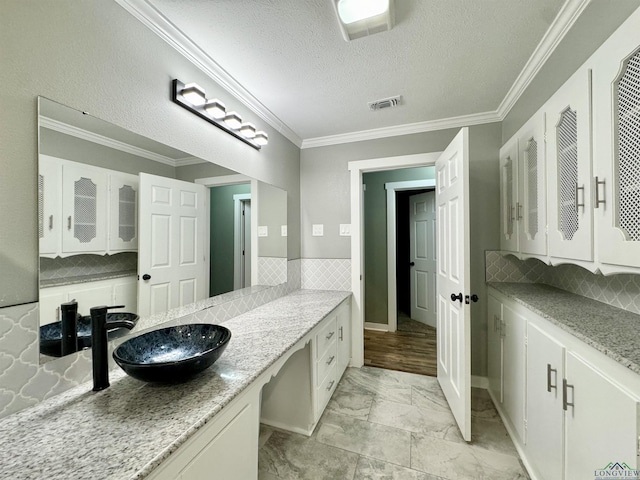 2305 Buccaneer Dr, Longview, TX 75604 - bathroom featuring marble finish flooring, backsplash, a textured ceiling, ornamental molding, and vanity