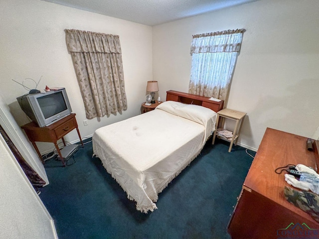 bedroom featuring dark carpet, a textured ceiling, and baseboards