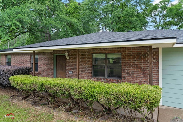 single story home featuring roof with shingles and brick siding
