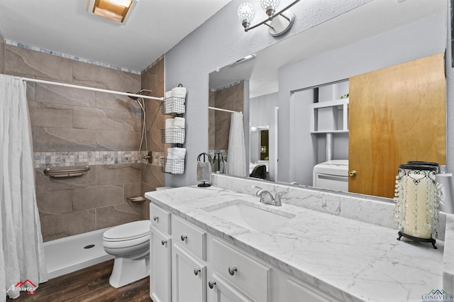 bathroom with toilet, wood finished floors, tiled shower, and vanity