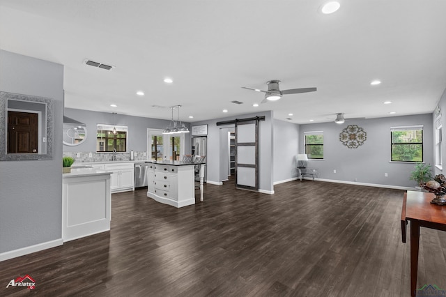 kitchen with a barn door, ceiling fan, stainless steel dishwasher, recessed lighting, and white cabinets