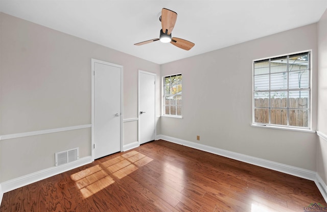 unfurnished bedroom with ceiling fan, wood-type flooring, and multiple windows