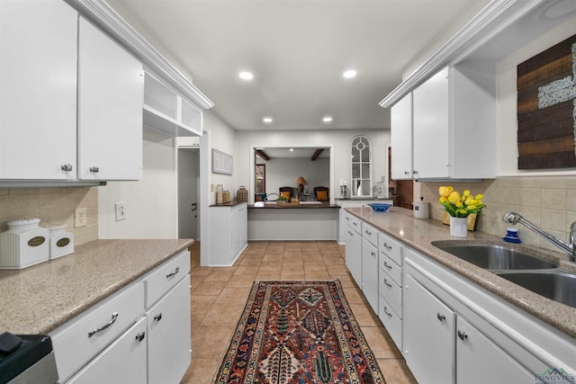 kitchen with backsplash, sink, white cabinets, and light tile patterned floors