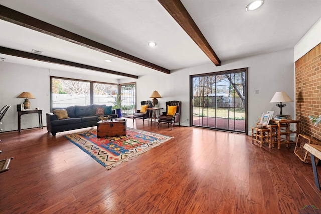 living room featuring beam ceiling, plenty of natural light, and hardwood / wood-style floors