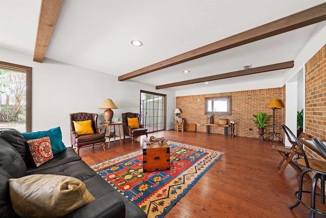 living room featuring hardwood / wood-style floors, beamed ceiling, and brick wall