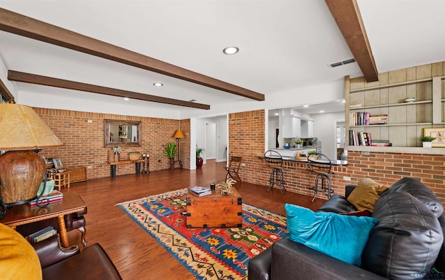 living room with dark hardwood / wood-style floors, beam ceiling, and brick wall