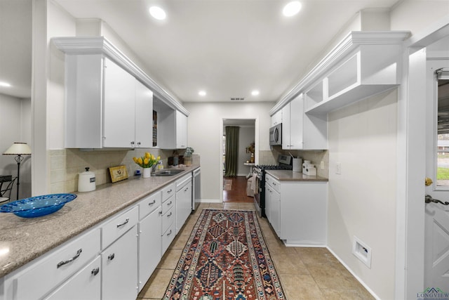 kitchen with white cabinets, light tile patterned floors, appliances with stainless steel finishes, and tasteful backsplash