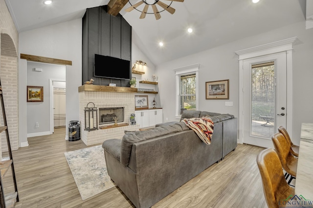 living room featuring light hardwood / wood-style floors, beamed ceiling, ceiling fan, high vaulted ceiling, and a fireplace