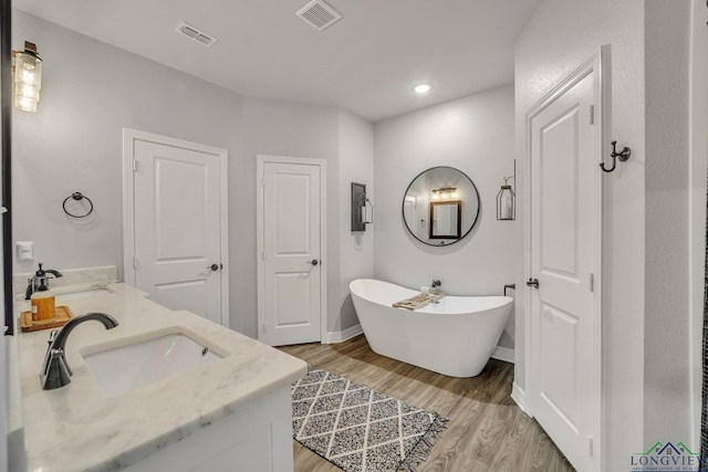 bathroom with vanity, a tub to relax in, and hardwood / wood-style floors