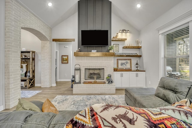 living room featuring light hardwood / wood-style floors, lofted ceiling, and a fireplace