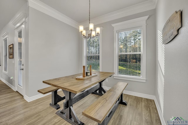 dining space featuring light wood-type flooring, a notable chandelier, and crown molding