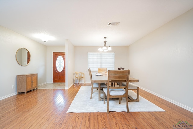 dining space featuring a notable chandelier and light wood-type flooring