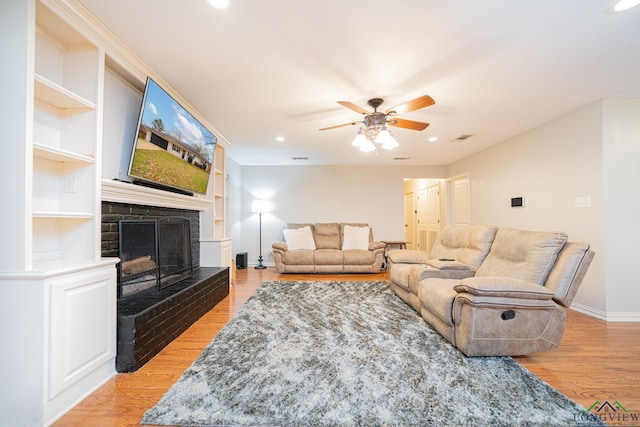 living room with built in shelves, ceiling fan, and light hardwood / wood-style floors