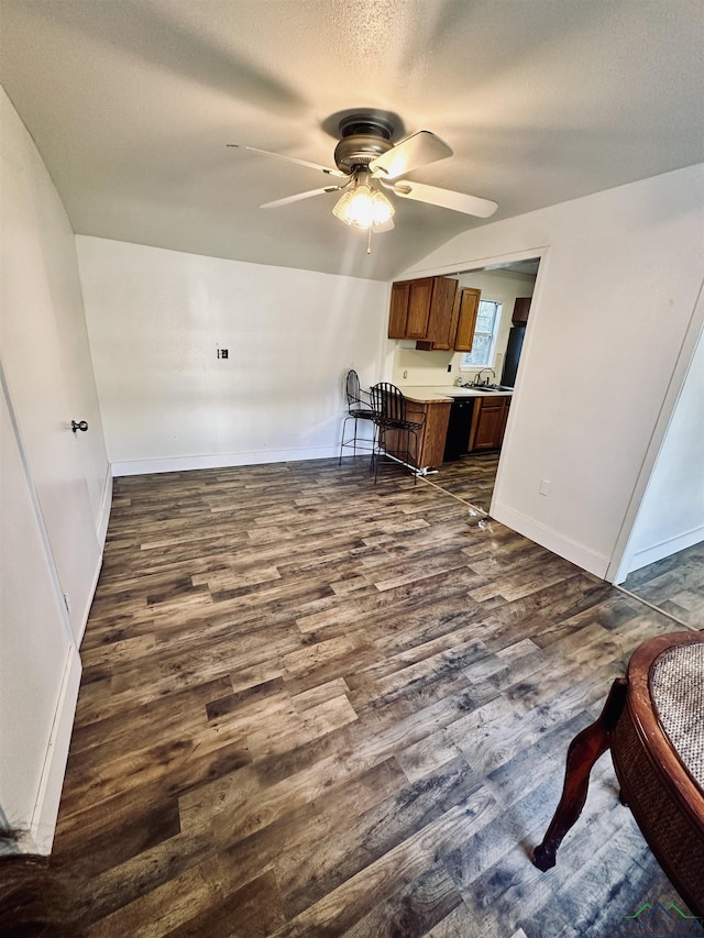 living room with ceiling fan, sink, dark wood-type flooring, and a textured ceiling