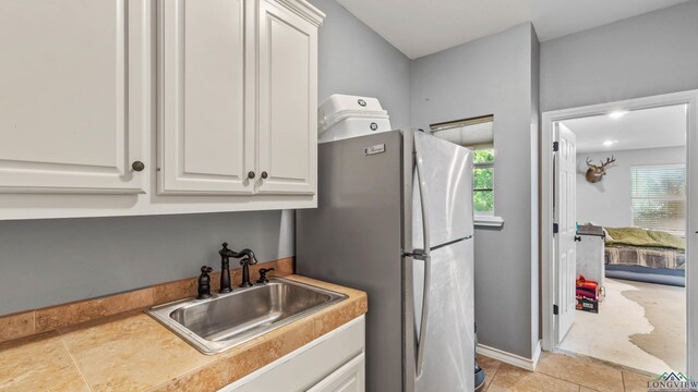 128 Inwood Rd, Texarkana, TX 75501 - kitchen featuring light countertops, freestanding refrigerator, a sink, and white cabinets
