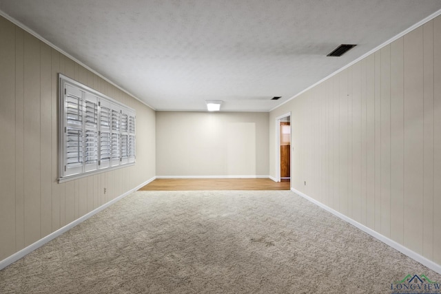 empty room with carpet flooring, visible vents, ornamental molding, and baseboards