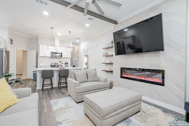 living room with ornamental molding, light wood-style floors, visible vents, and a fireplace