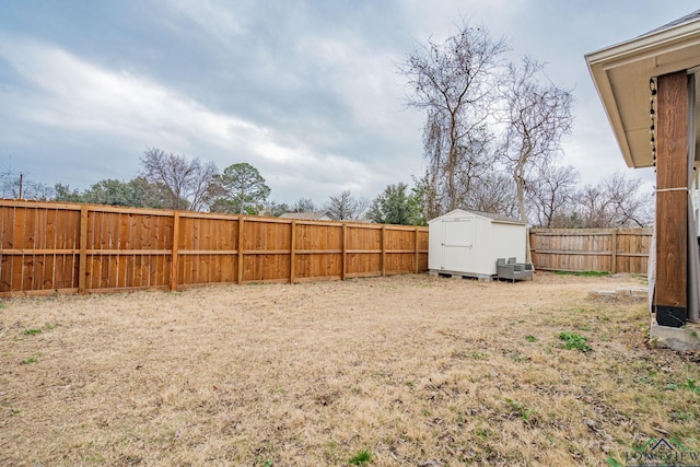 view of yard with an outbuilding, a storage shed, and a fenced backyard