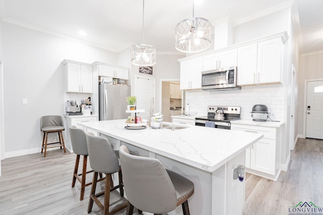 kitchen with white cabinetry, appliances with stainless steel finishes, a kitchen breakfast bar, and crown molding