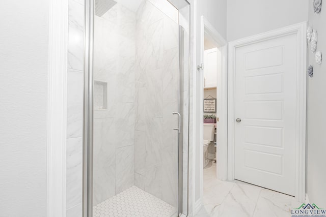 bathroom featuring toilet, marble finish floor, and a marble finish shower