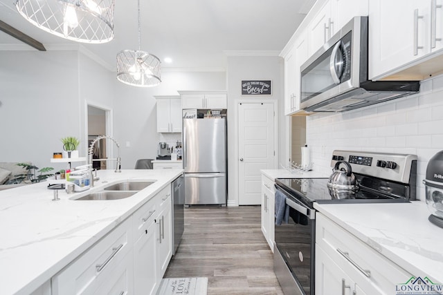 kitchen with stainless steel appliances, white cabinetry, a sink, and ornamental molding