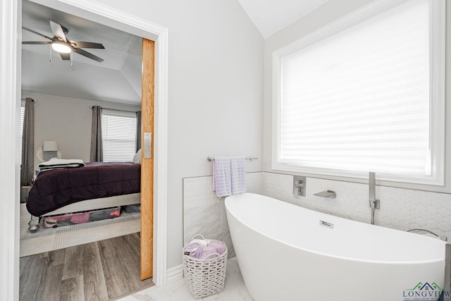 bathroom with a freestanding tub, ceiling fan, vaulted ceiling, and connected bathroom