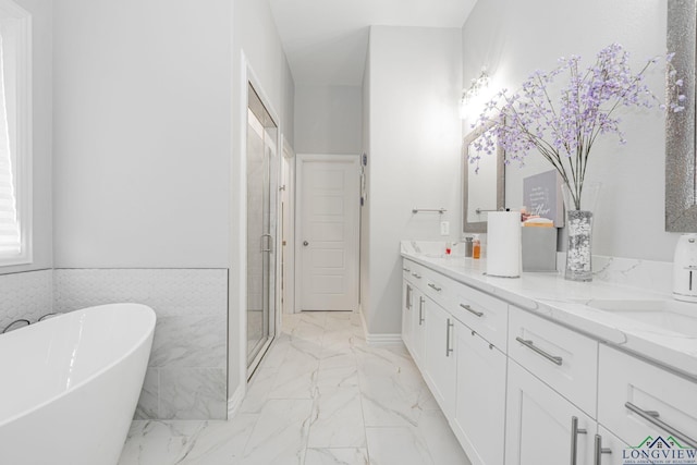 bathroom with a sink, marble finish floor, a soaking tub, a shower stall, and double vanity