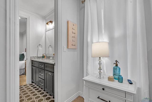 ensuite bathroom featuring baseboards, ornamental molding, ensuite bathroom, and vanity
