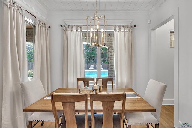dining area featuring ornamental molding, a notable chandelier, wood finished floors, and a healthy amount of sunlight