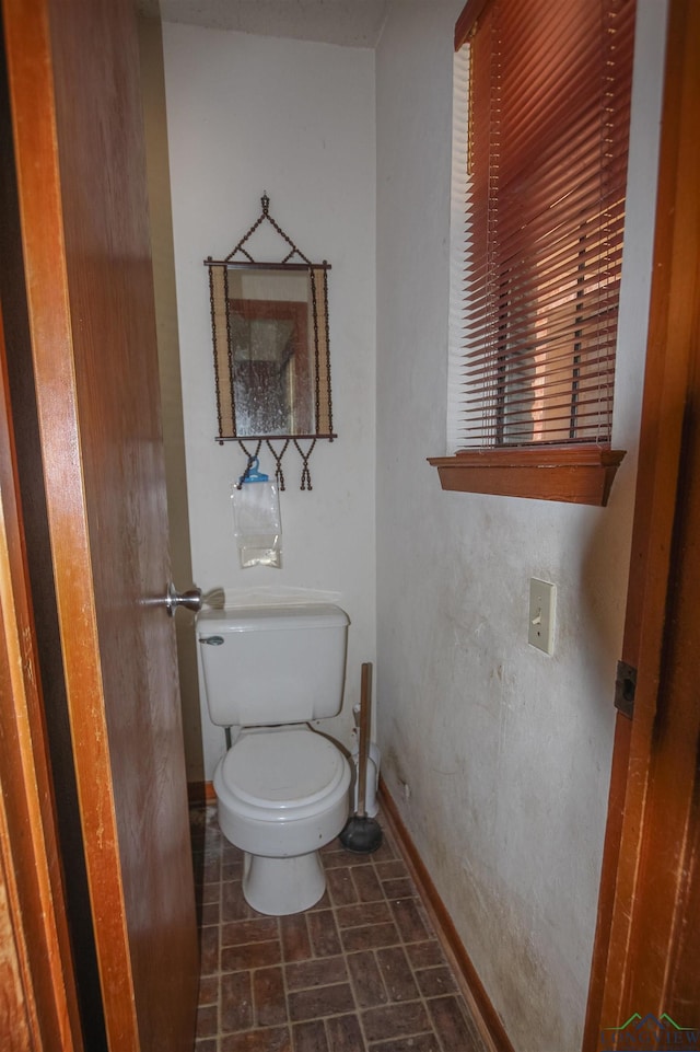 1006 Quitman St, Pittsburg, TX 75686 - bathroom with toilet, baseboards, and brick patterned floors