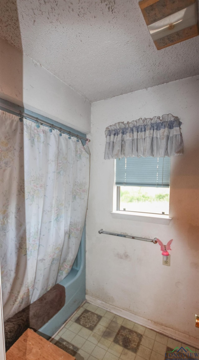 1006 Quitman St, Pittsburg, TX 75686 - full bathroom featuring a textured ceiling, shower / bathtub combination with curtain, tile patterned floors, and baseboards