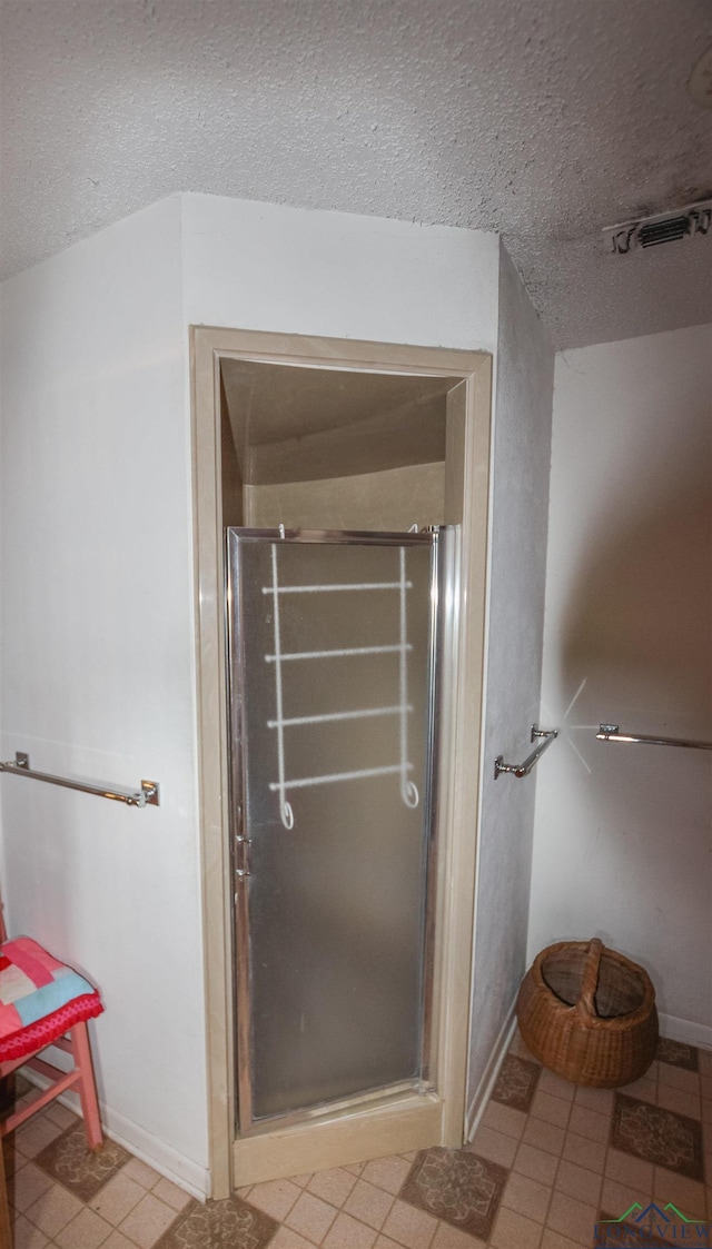 1006 Quitman St, Pittsburg, TX 75686 - bathroom with a stall shower, a textured ceiling, and baseboards