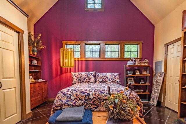 bedroom featuring high vaulted ceiling and dark tile patterned flooring