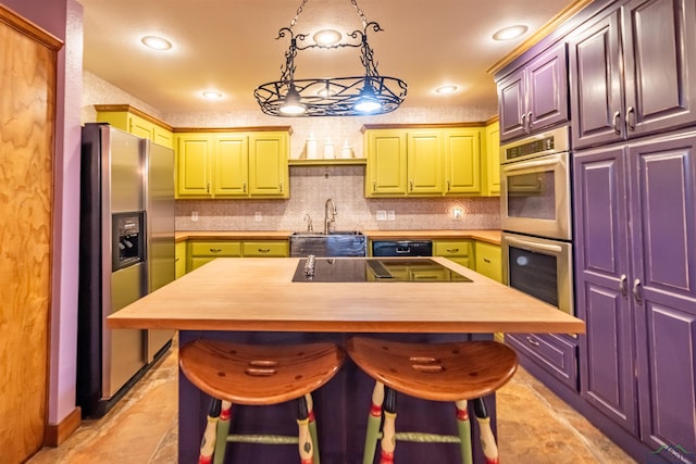 kitchen featuring a kitchen bar, butcher block counters, a kitchen island, and appliances with stainless steel finishes